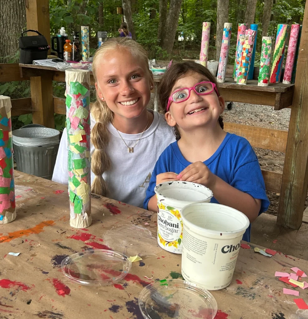 Volunteer and child smiling while creating art together at Wings of Eagles Ranch.