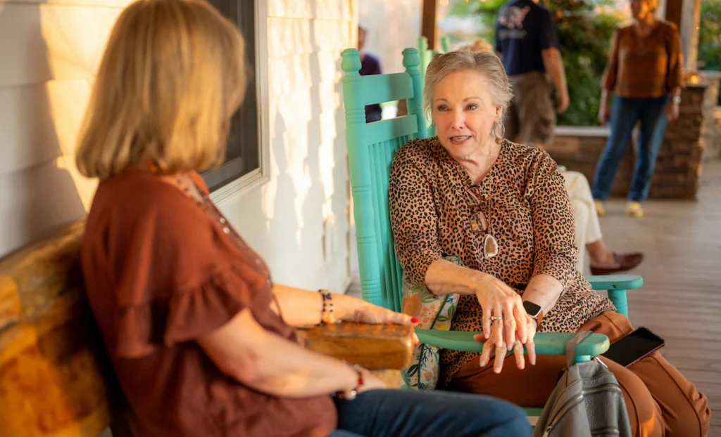 Guests relaxing and talking on the porch at a retreat cabin at Wings of Eagles Ranch.