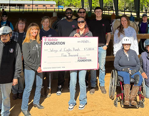 Community members and riders gather in the arena as Wings of Eagles Ranch receives a grant presentation from the T-Mobile Foundation.