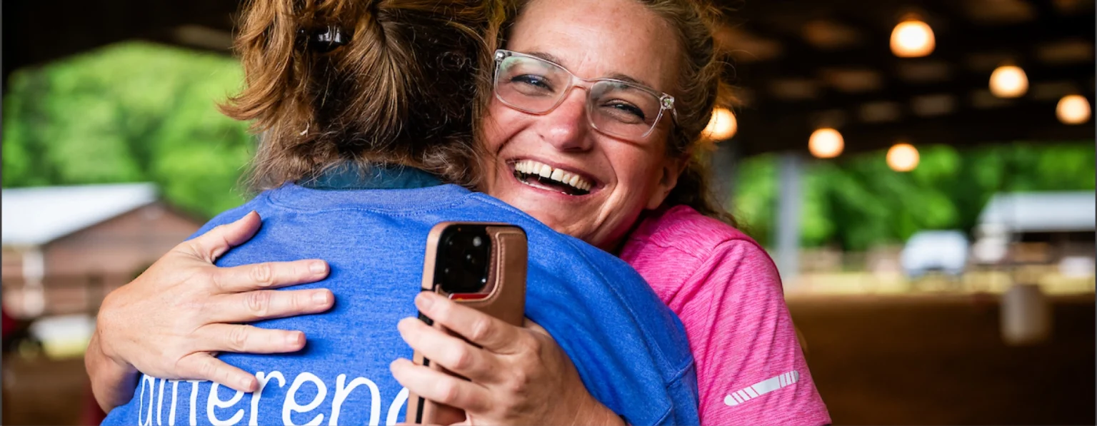 Volunteer and participant sharing a joyful hug at Wings of Eagles Ranch.
